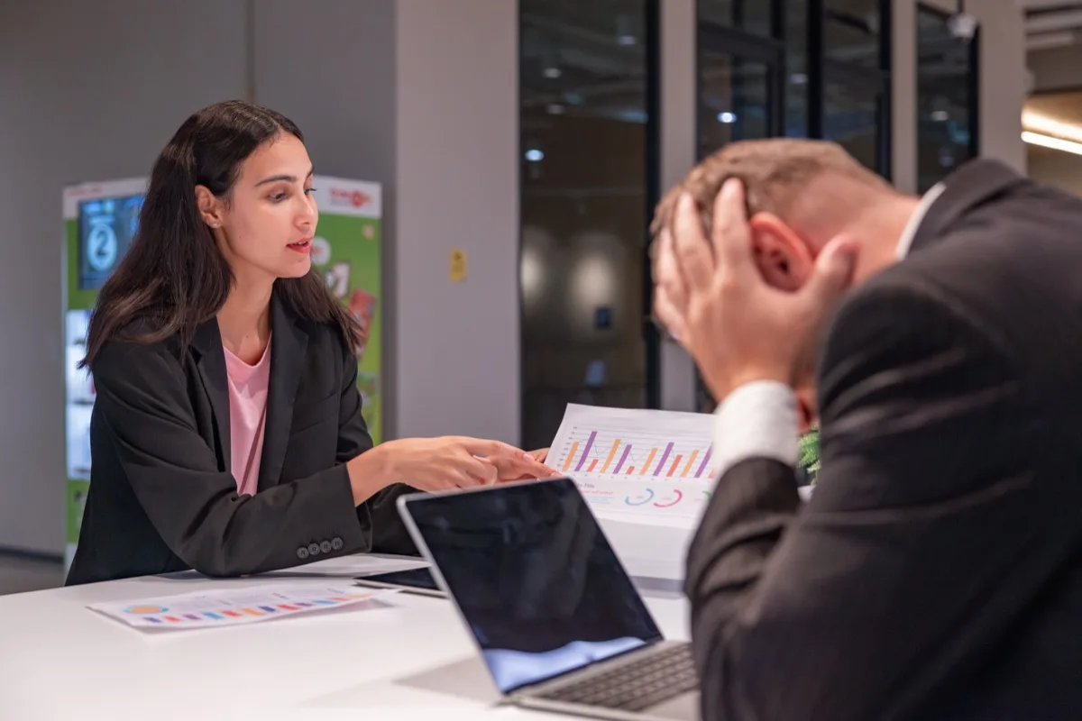 A stressed employee during a traditional corporate performance review meeting.